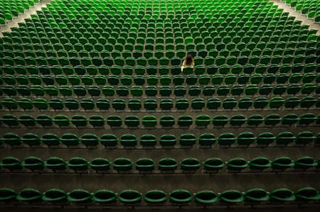 A caucasian woman stands on an empty tribune of a stadium. Female cheerleader.の写真素材