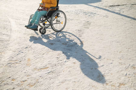 Close-up of hands of a disabled woman in a wheelchair outdoors in winter.の写真素材