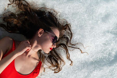 Close-up portrait of a caucasian woman lying on the snow.の写真素材