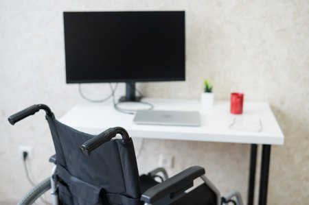 Workplace for a disabled person. Wheelchair at the table with a computer.