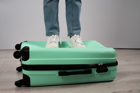 Woman standing with her feet on a suitcase.