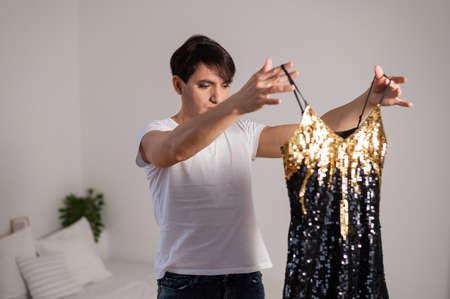 Gay trying on a shiny dress. The transgender chooses the outfit for the party.