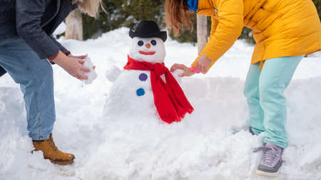 Two Caucasian women are making a snowman. Winter fun.