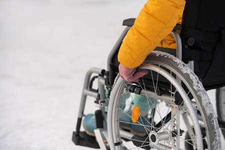 Close-up of hands of a disabled woman in a wheelchair outdoors in winter.の写真素材