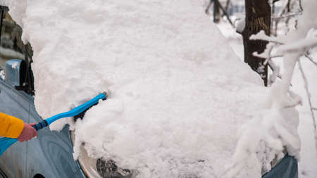 Caucasian woman brushing a car from freshly fallen snow.の写真素材