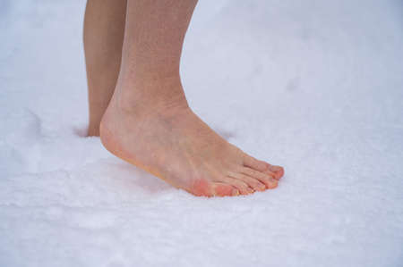 Close-up of a woman walking barefoot in the snow. Boosting immunity with cryotherapy.