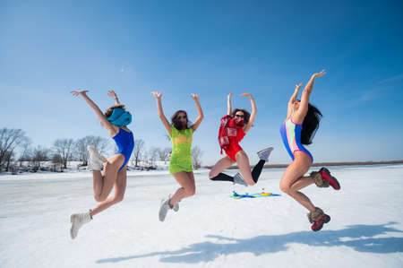 Four Caucasian women in swimsuits are fooling around on a snowy beach. Winter fun.の写真素材