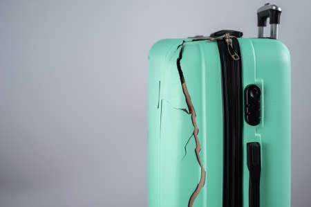 Close-up of a broken plastic suitcase on a white background.の写真素材