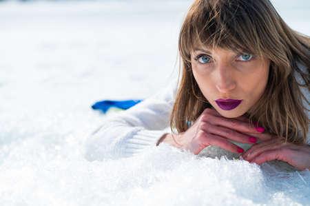 Close-up portrait of a caucasian woman lying on the snow.の写真素材