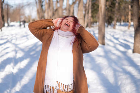 Cheerful fat caucasian woman in fur headphones outdoors.の写真素材