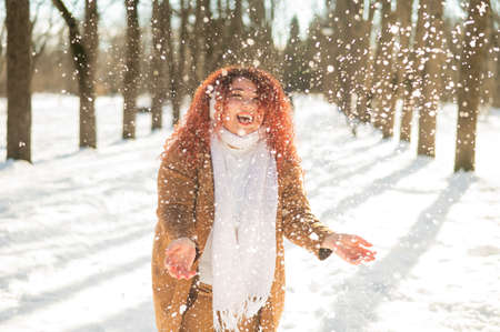 Fat caucasian woman playing snowballs in the park.