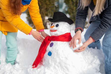 Two faceless Caucasian women are making a snowman. Winter fun.の写真素材