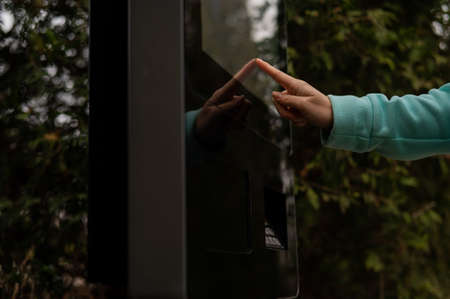 Caucasian woman chooses on the touch screen of a modern terminal for payment while standing on the...