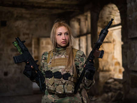 Blonde woman in army uniform holding a firearm in an abandoned building.