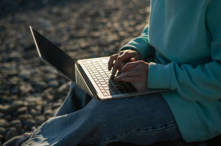 Close-up of a caucasian womans hands finishing typing and close up. Freelancer working on a pebble beach.の写真素材