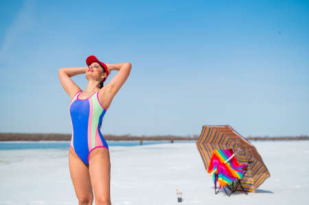 Caucasian woman in a swimsuit sunbathes on the snow in winter.