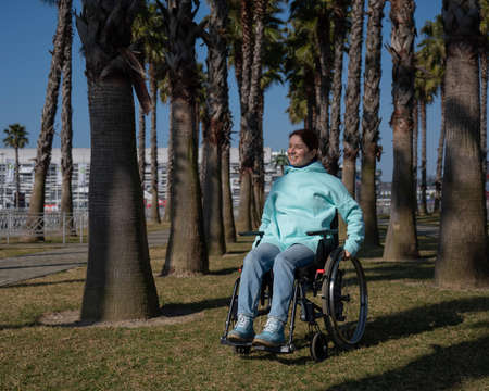 Caucasian woman in wheelchair under palm trees.の写真素材