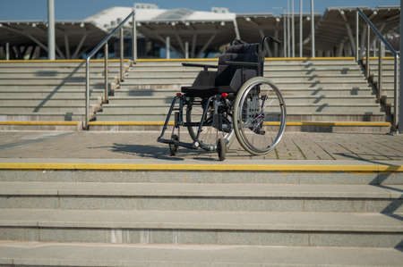 Abandoned wheelchair by the stairs. Hard to access environment.の写真素材