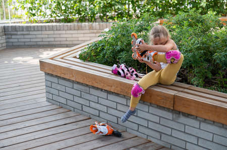 Little girl learns to roller skate outdoors.