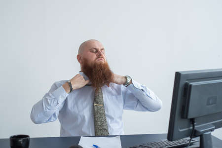 Problems for the office worker. A bald man in a white shirt sits at a desk with a computer and is stressed because of failure. A nervous breakdown.の写真素材
