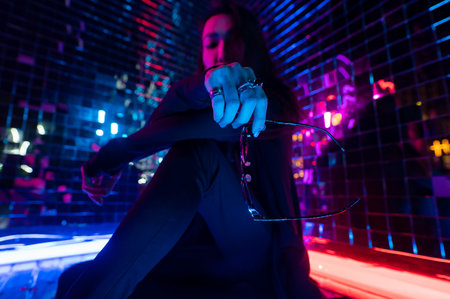 Asian man holding sunglasses. Neon photo studio.の写真素材