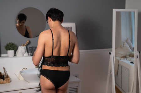 Homosexual preening in front of the mirror. A transgender man combing a wig.の写真素材