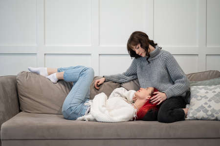 Young girls hugging while lying on the couch. Unisexual love.