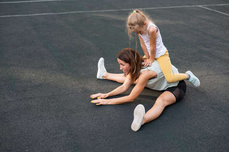 Mother and daughter go in for sports outdoors. Caucasian woman and little girl are engaged in...