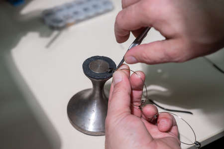 Optical technician fixing glasses. Close-up of male hands with screwdriver and goggles frame.