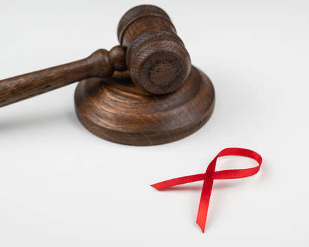 Judicial gavel and red ribbon on a white background. Symbol of the fight against AIDS.の写真素材