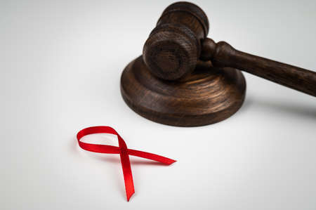 Judicial gavel and red ribbon on a white background. Symbol of the fight against AIDS.の写真素材