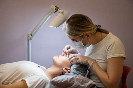 The master cleans the eyelashes of a woman preparing before lamination.