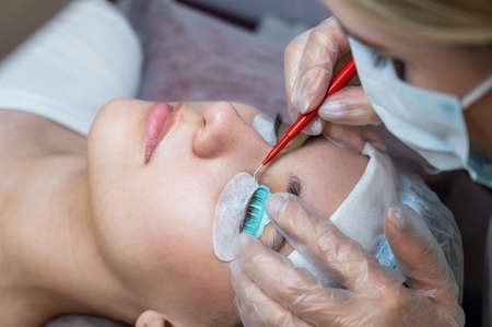 The master uses a multifunctional tool for laminating eyelashes.