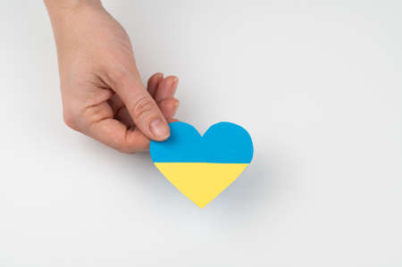 A woman holds a heart with the flag of Ukraine on a white background.の写真素材