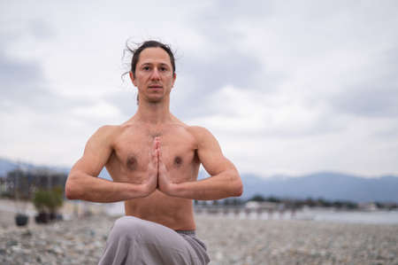 Caucasian man with naked torso practicing wushu on the seashore.の写真素材