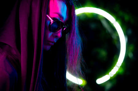 Portrait of asian man in hood and sunglasses in neon light.