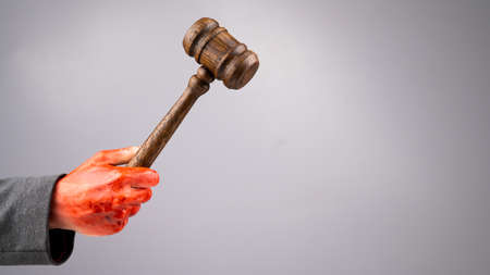A female judge holds a gavel in a bloody hand on a white background. Copy space.