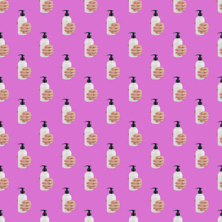 A womans hand sticks out of a hole in a pink paper background and holds a skin lotion pump. Endless pattern.の写真素材