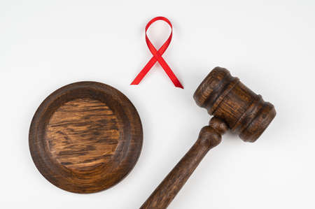 Judicial gavel and red ribbon on a white background. Symbol of the fight against AIDS.