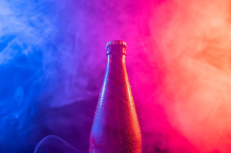 Glass bottle of beer in blue pink mistの写真素材