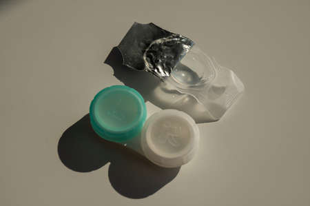 Contact lenses and a storage container on a white table.