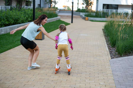 Caucasian woman teaches her daughter to skate on roller skates.の写真素材