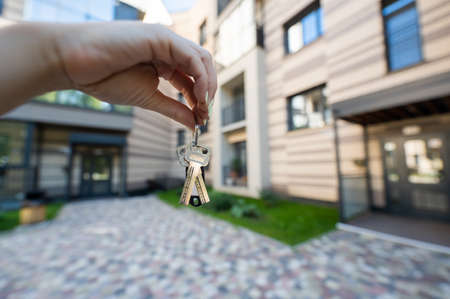 A woman holds the keys to a new house. Close-up of a female hand. Buying a property.の写真素材