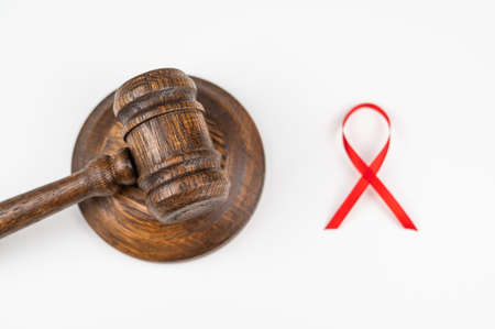 Judicial gavel and red ribbon on a white background. Symbol of the fight against AIDS.の写真素材