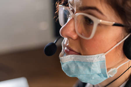 Female employee of the call center took off the medical mask at the workplace.