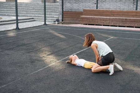 Mother and daughter go in for sports outdoors. Caucasian woman and little girl are engaged in fitness at the stadium.の写真素材