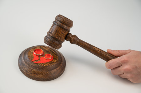 The judge hits the gavel on a broken heart and wedding rings.の写真素材