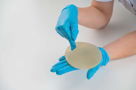 A plastic surgeon shows a breast silicone implant.