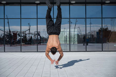 A man doing a handstand outdoors against the backdrop of panoramic windows.の写真素材