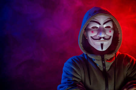 June 5, 2022 Novosibirsk, Russia: Hooded portrait of Anonymous in the dark in red-blue smoke.のeditorial素材
